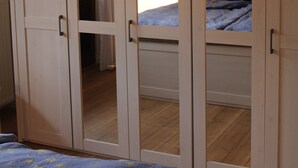 Une chambre à coucher comprenant un lit, une armoire et une porte donnant sur une autre pièce.