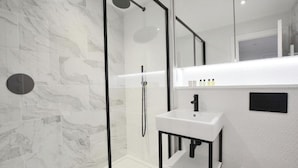 Ein modernes Badezimmer mit einer Duschkabine aus Glas, einem weißen Waschbecken und einem Spiegel darüber.