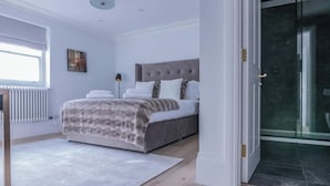 Ein Schlafzimmer mit Bett, Nachttisch, Lampe und Fenster.