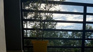 A spacious room with a large window, a potted plant, and a shiny tiled floor. - The Grand Kalimpong (Kalimpong)