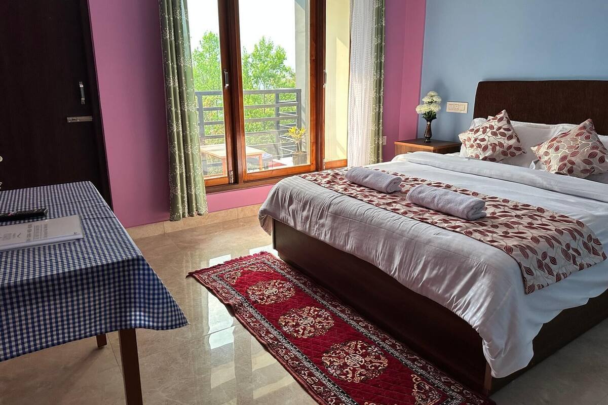 Un dormitorio con una cama grande, una mesa con mantel a cuadros y un tapete de diseño rojo.