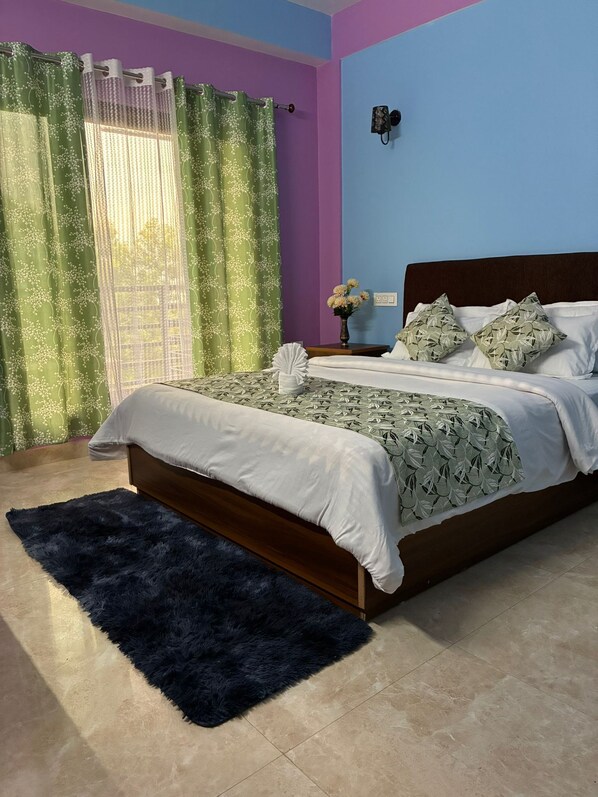 Un dormitorio con cama, una mesita de noche, un florero con flores y una pared azul.