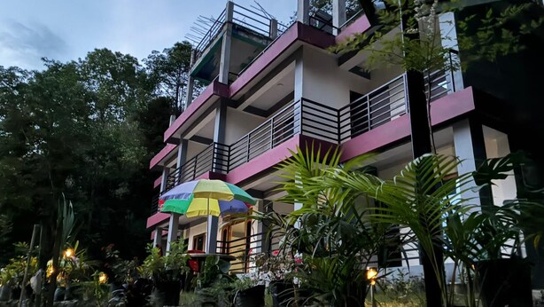 A multi-story building with balconies, surrounded by lush greenery and a small waterfall feature. - The Grand Kalimpong (Kalimpong)