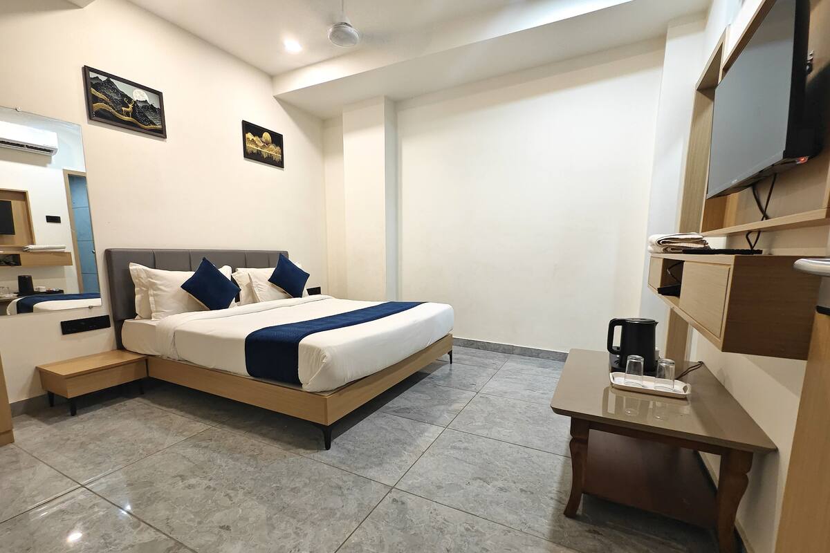 Een moderne hotelkamer met een groot bed, nachtkastjes, een bureau en een flatscreen televisie.