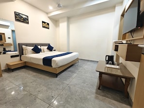 A modern hotel room with a large bed, bedside tables, a desk, and a flat-screen TV. - Hotel Krisha, Dwarka (Dwarka)