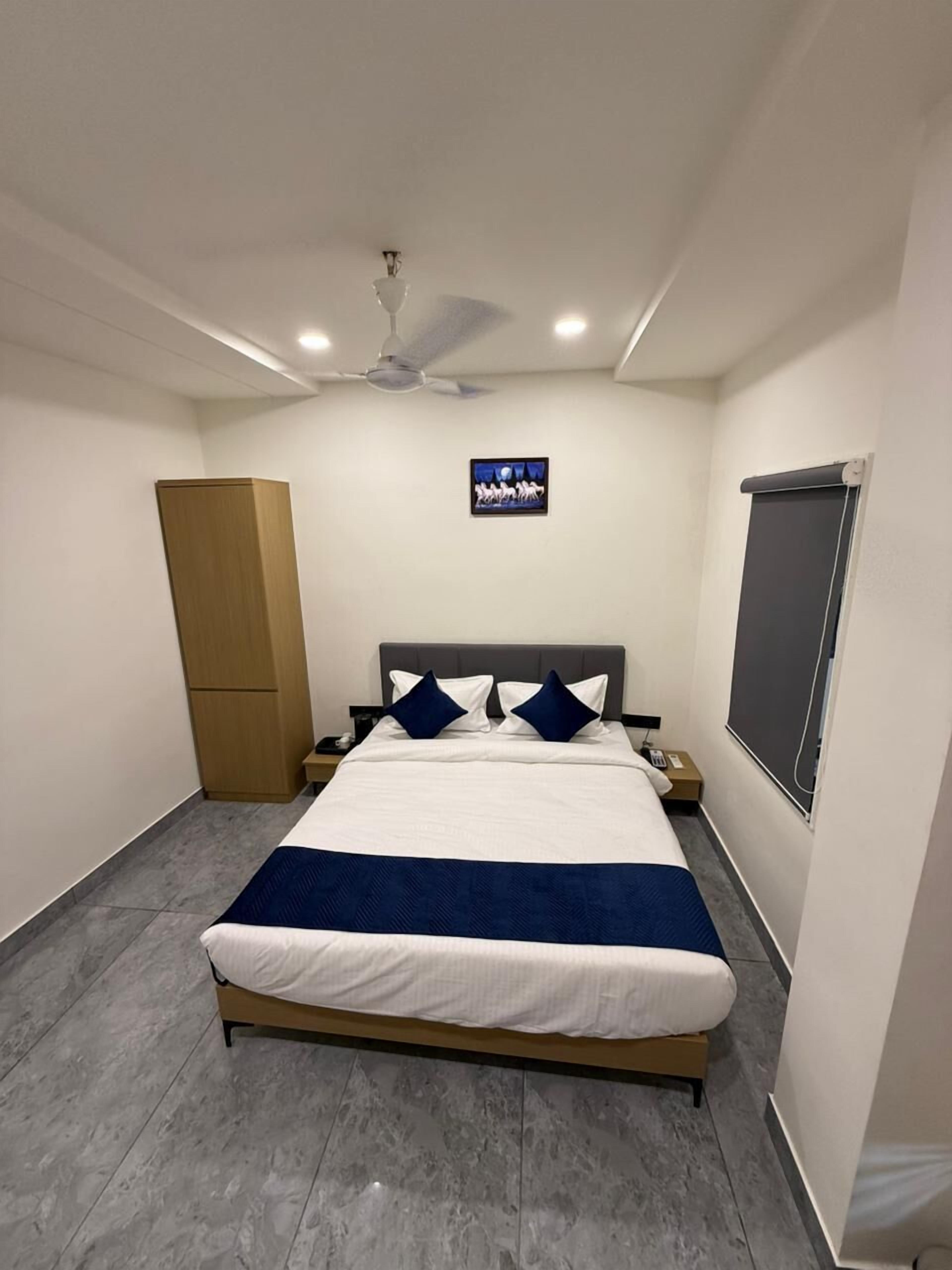 A bedroom with a bed, a ceiling fan, a nightstand, a wardrobe, and a wall-mounted TV.