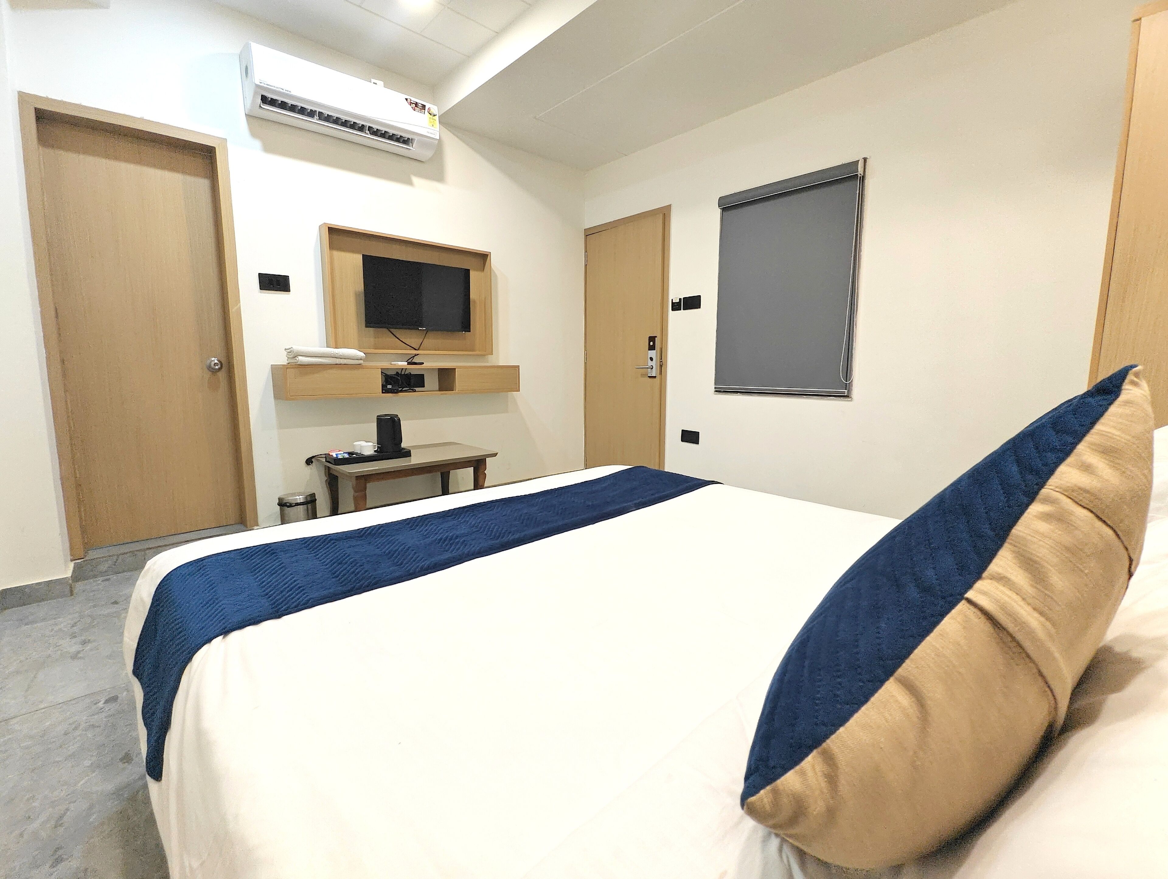 Een hotelkamer met een bed, een televisie, een bureau en een raam.