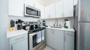 Eine moderne Küche mit Edelstahlgeräten, weißen Schränken und einer Arbeitsplatte aus Granit.