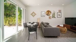 Ein modernes Wohnzimmer mit Essbereich, einem grauen Sofa, einem Fernseher und Kunstwerken an der Wand.
