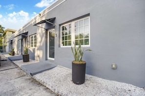 Un edificio moderno con fachada gris, ventanas grandes y plantas en macetas.