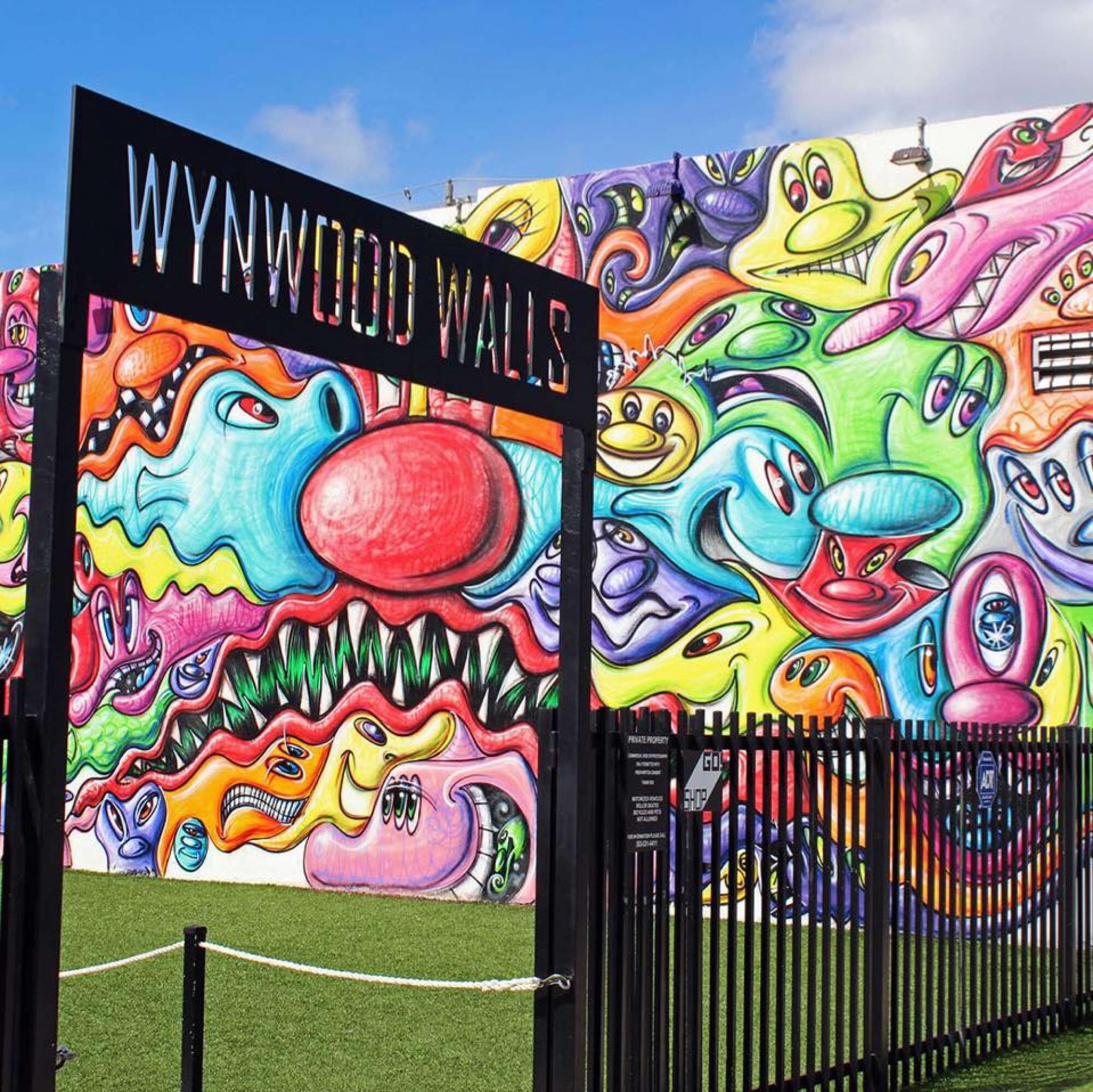 Une fresque murale colorée, ornée de personnages fantaisistes, et sur laquelle on peut lire l’inscription « WYNWOOD WALLS », sur la façade d’un immeuble.