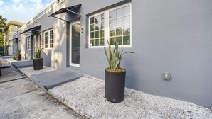 A modern building with large windows, a grey exterior, and potted plants in front. - Designer Studio | Close to Wynwood | Design District  | Downtown (Miami)
