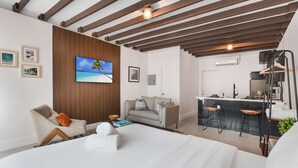 A modern hotel room with a large bed, a sofa, a TV, a kitchen area, and a wooden ceiling. - Designer Studio | Close to Wynwood | Design District  | Downtown (Miami)