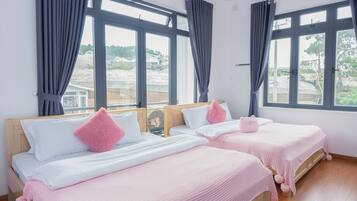 Quarto com duas camas, janelas amplas e vista para o exterior.