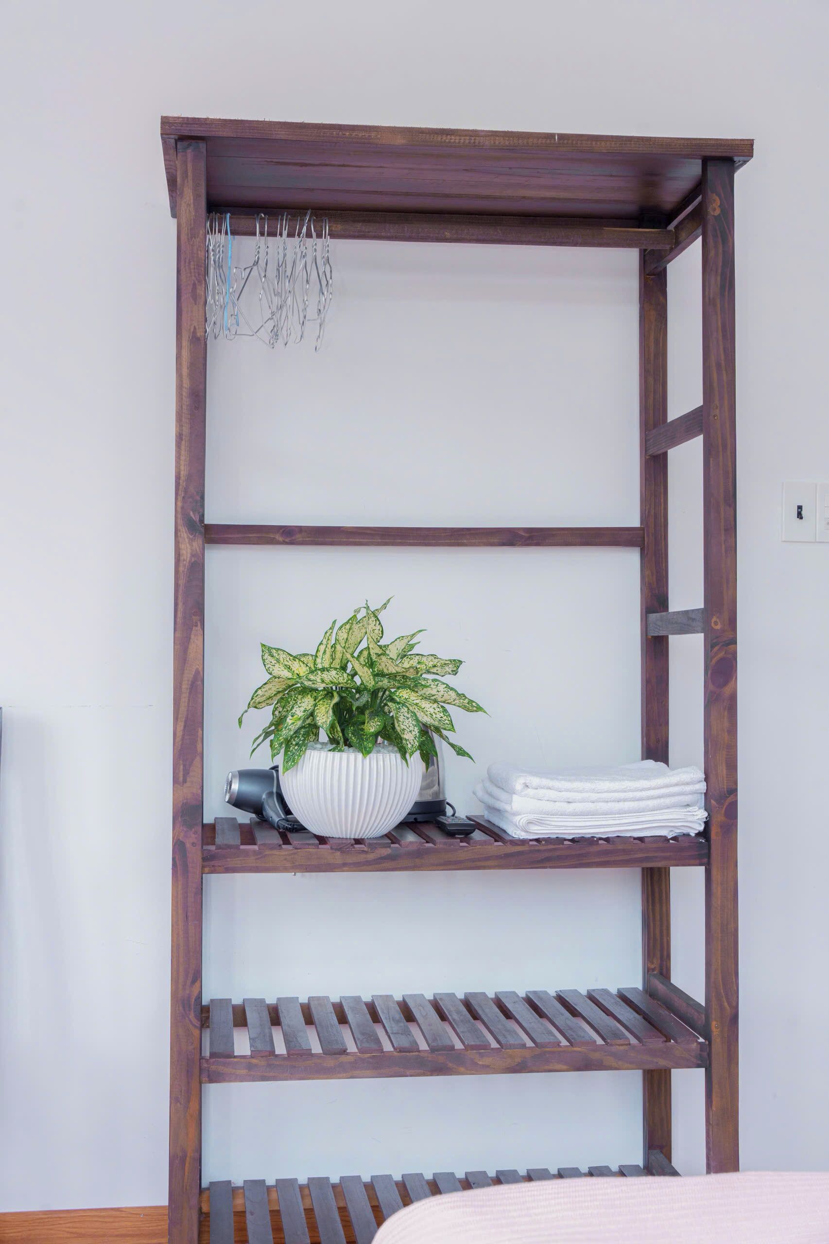 Une étagère en bois avec une plante en pot et des serviettes pliées.