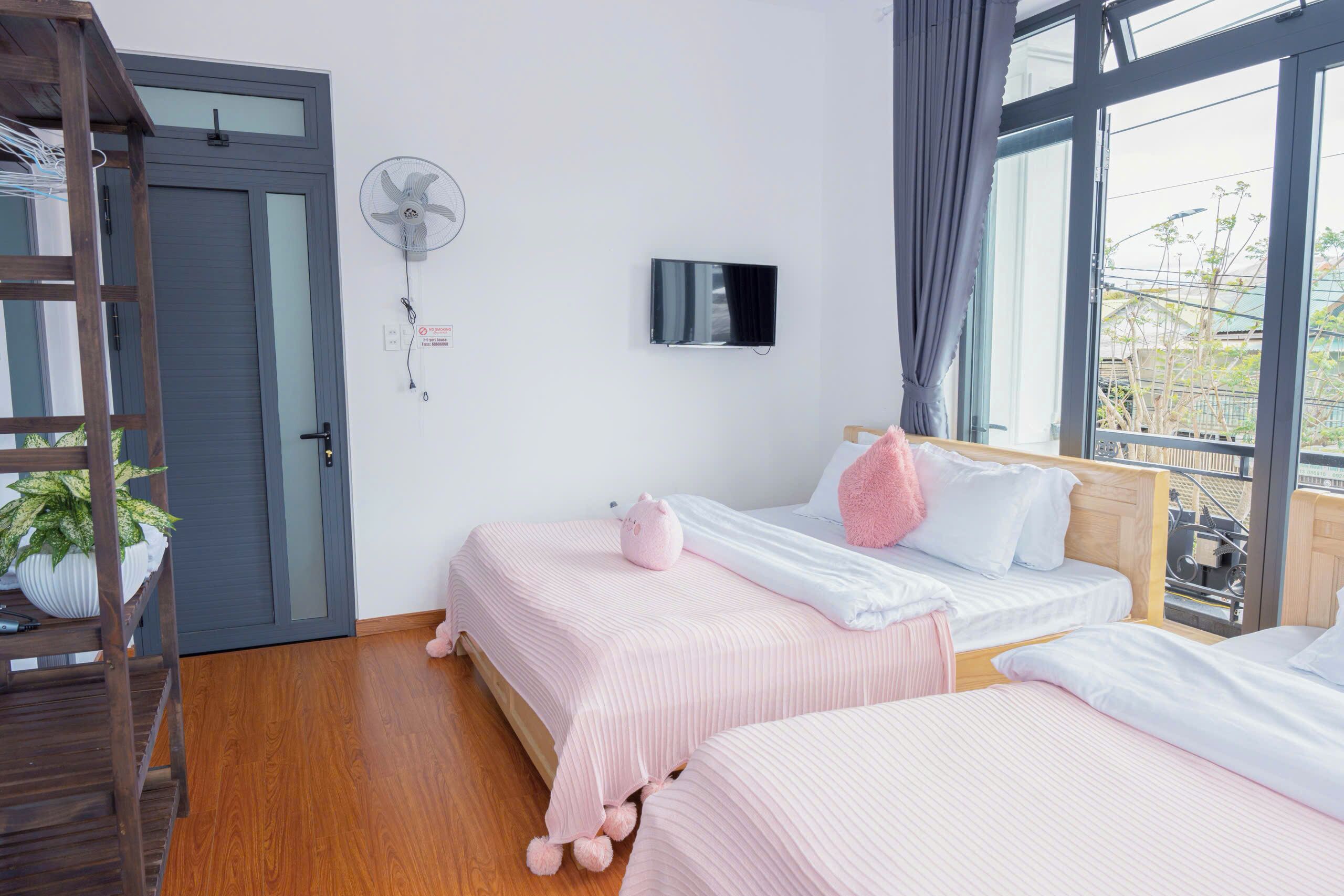 Un dormitorio con dos camas, televisión, ventilador y ventana con vistas.