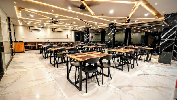 A spacious dining area with multiple tables and chairs, ceiling fans, and a marble floor.