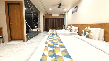 A hotel room with a long bed, a wooden headboard, and a ceiling fan.