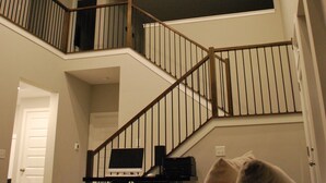 A multi-level home interior with a staircase, a television on a stand, and a couch with pillows. - Charming Suite in a Spacious Shared Home in Fishers – Utilities included (Fishers)