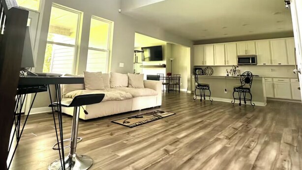 A spacious living area with a high ceiling, a sofa, a dining table, and a kitchen in the background. - Charming Suite in a Spacious Shared Home in Fishers – Utilities included (Fishers)