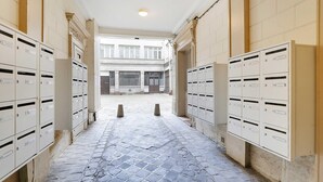 A corridor with mailboxes on both sides and a cobblestone floor. - Cozy studio - 2P - Gare de l'Est (Paris)