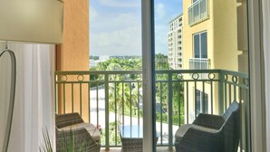 A balcony with wicker chairs, a potted plant, and a view of a building and palm trees. - W Hotel SOUTH BEACH 1B RESIDENCE w/OCEAN VIEW - 909 (Key Biscayne Miami)