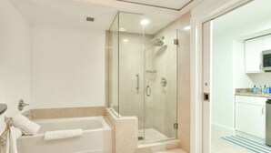 A modern bathroom with a glass-enclosed shower, a bathtub with towels, and a visible kitchen area with cabinets and a microwave. - W Hotel SOUTH BEACH 1B RESIDENCE w/OCEAN VIEW - 909 (Key Biscayne Miami)