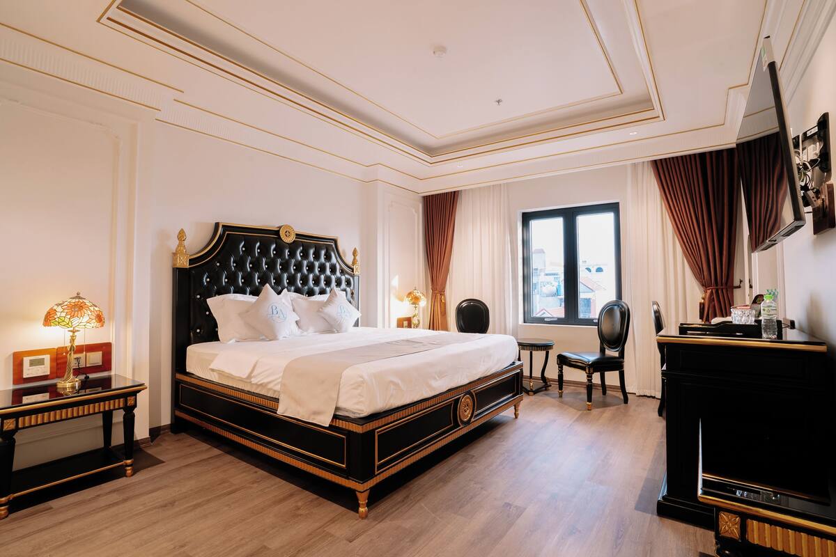 Una habitació d'hotel amb un llit gran, una taula de treball, una cadira i un piano.