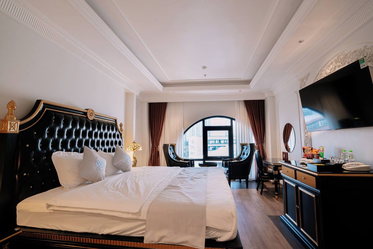 Una habitació d'hotel àmplia amb un llit gran, un escriptori i una televisió.