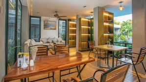 Sala de estar moderna com mesa de jantar de madeira, assentos confortáveis e vista para o verde lá fora.