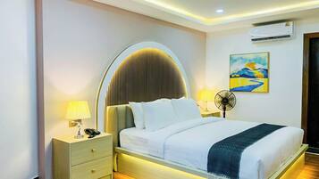 Ein modernes Hotelzimmer mit einem großen Bett, Nachttischen, einer Wand-Klimaanlage und einem Gemälde.