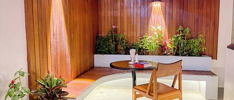 A modern interior with a wooden accent wall, a round table with a chair, and potted plants.