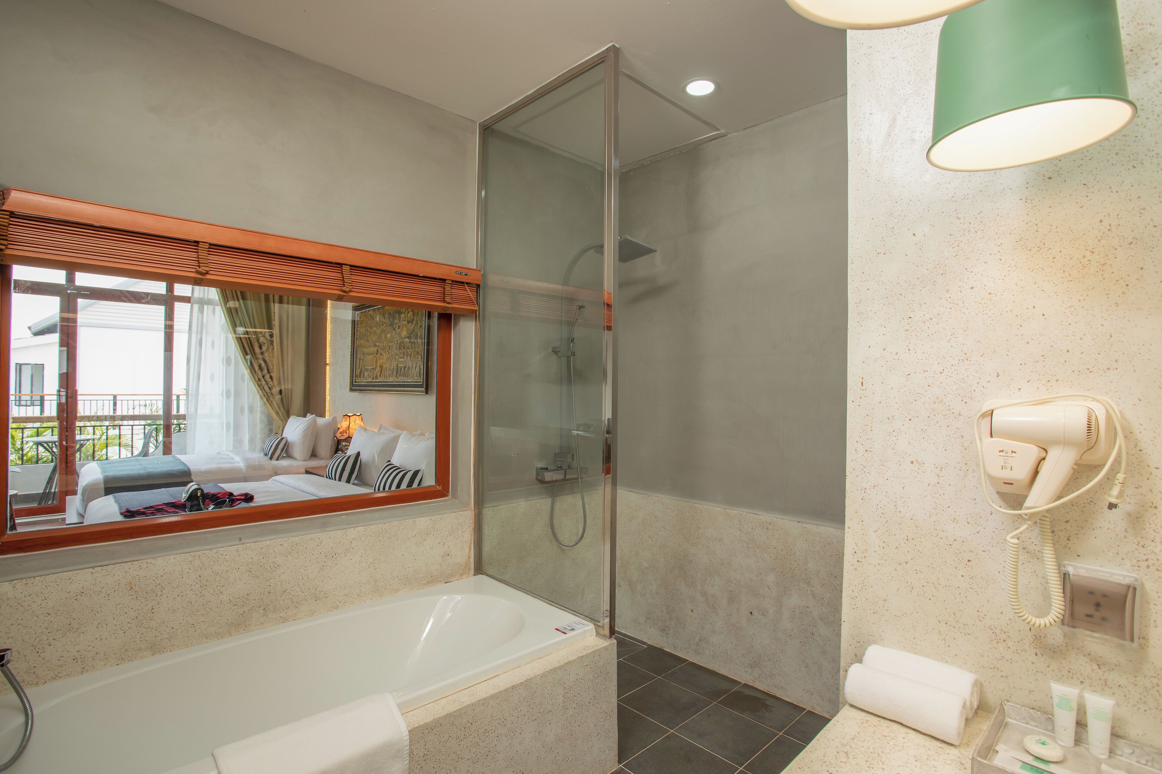 A modern bathroom with a glass-enclosed shower, a large bathtub, and a hairdryer mounted on the wall.