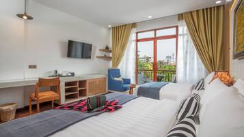 Habitación de hotel con cama, escritorio, silla, televisor y balcón con vistas.