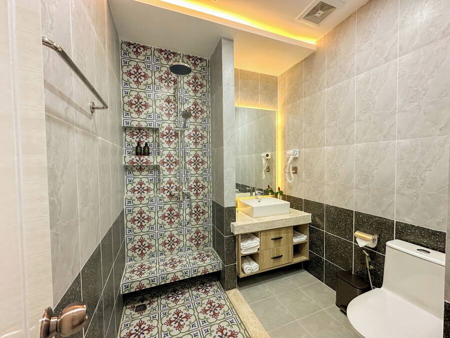 Een badkamer met een douche, wastafel, toilet en een badkamermeubel met handdoeken.
