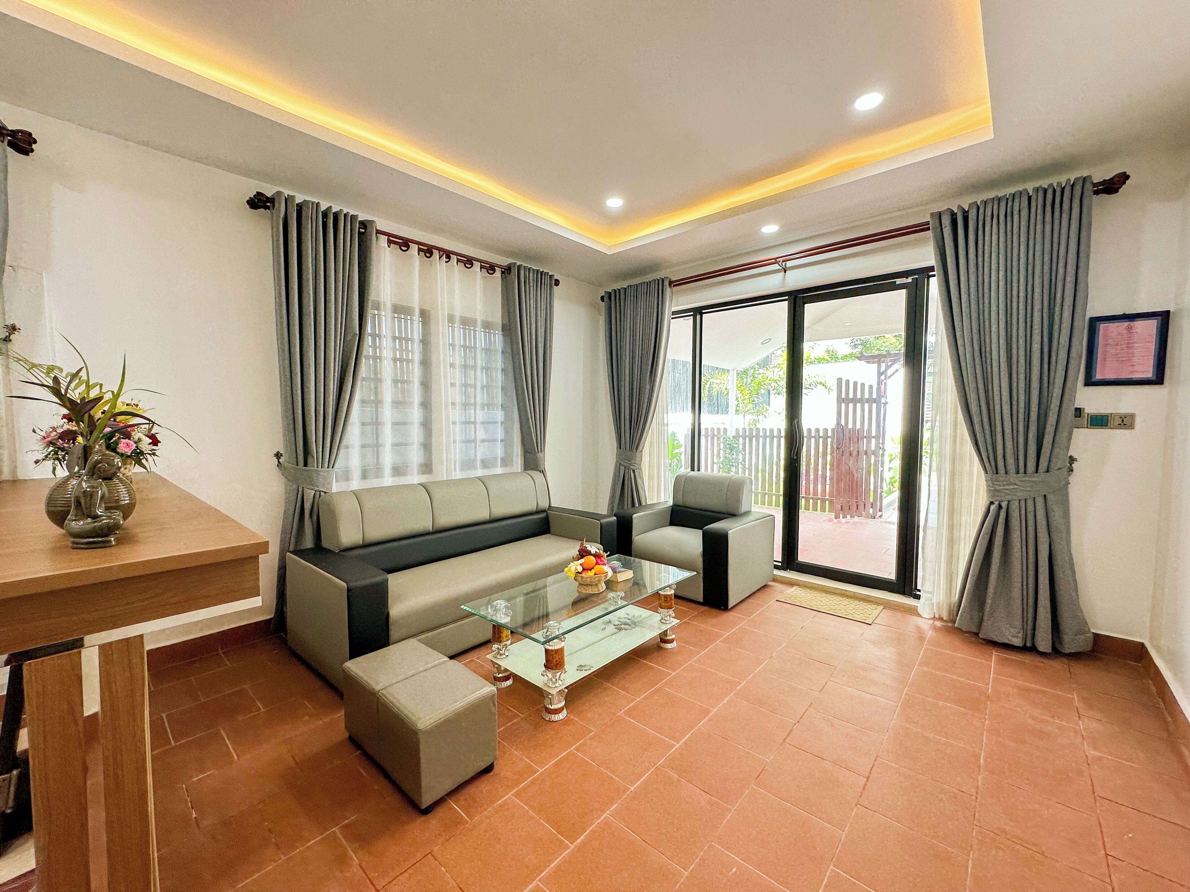 A modern living room with a sofa, armchair, glass coffee table, and a decorative vase.
