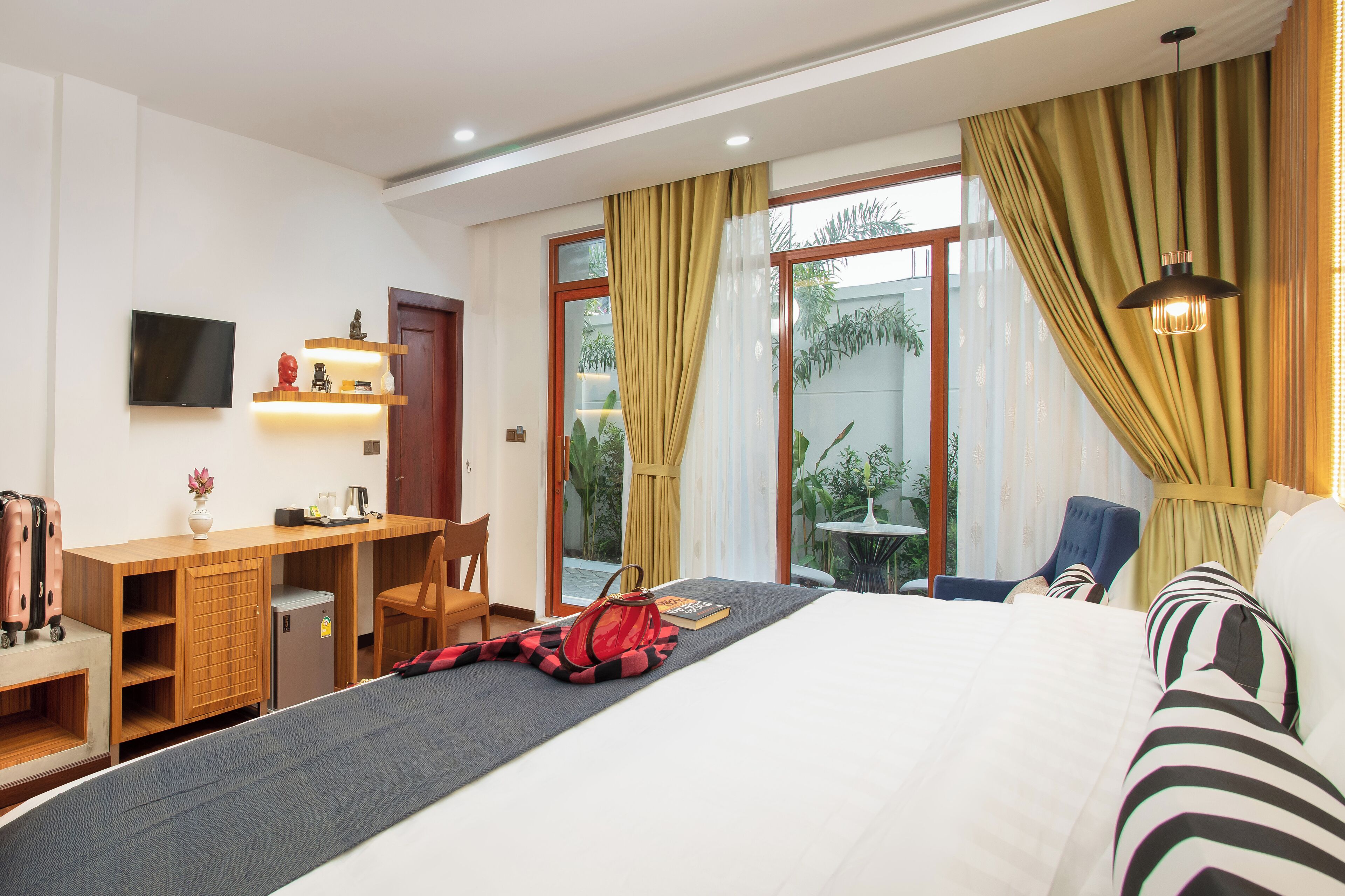 Ein Hotelzimmer mit Bett, Schreibtisch, Stuhl, Fernseher und Blick ins Freie.