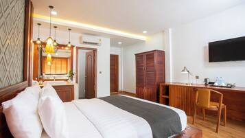 Una habitación de hotel con cama, escritorio, silla, televisor y espejo.