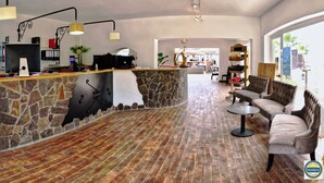 A spacious lobby with a stone reception desk, a comfortable seating area, and a view through large windows. - Bungalow on the sea - Moriani beach (Santa-Lucia-di-Moriani)