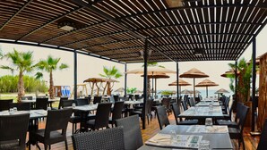 An outdoor restaurant with tables and chairs, umbrellas, and a view of the sea. - Bungalow on the sea - Moriani beach (Santa-Lucia-di-Moriani)