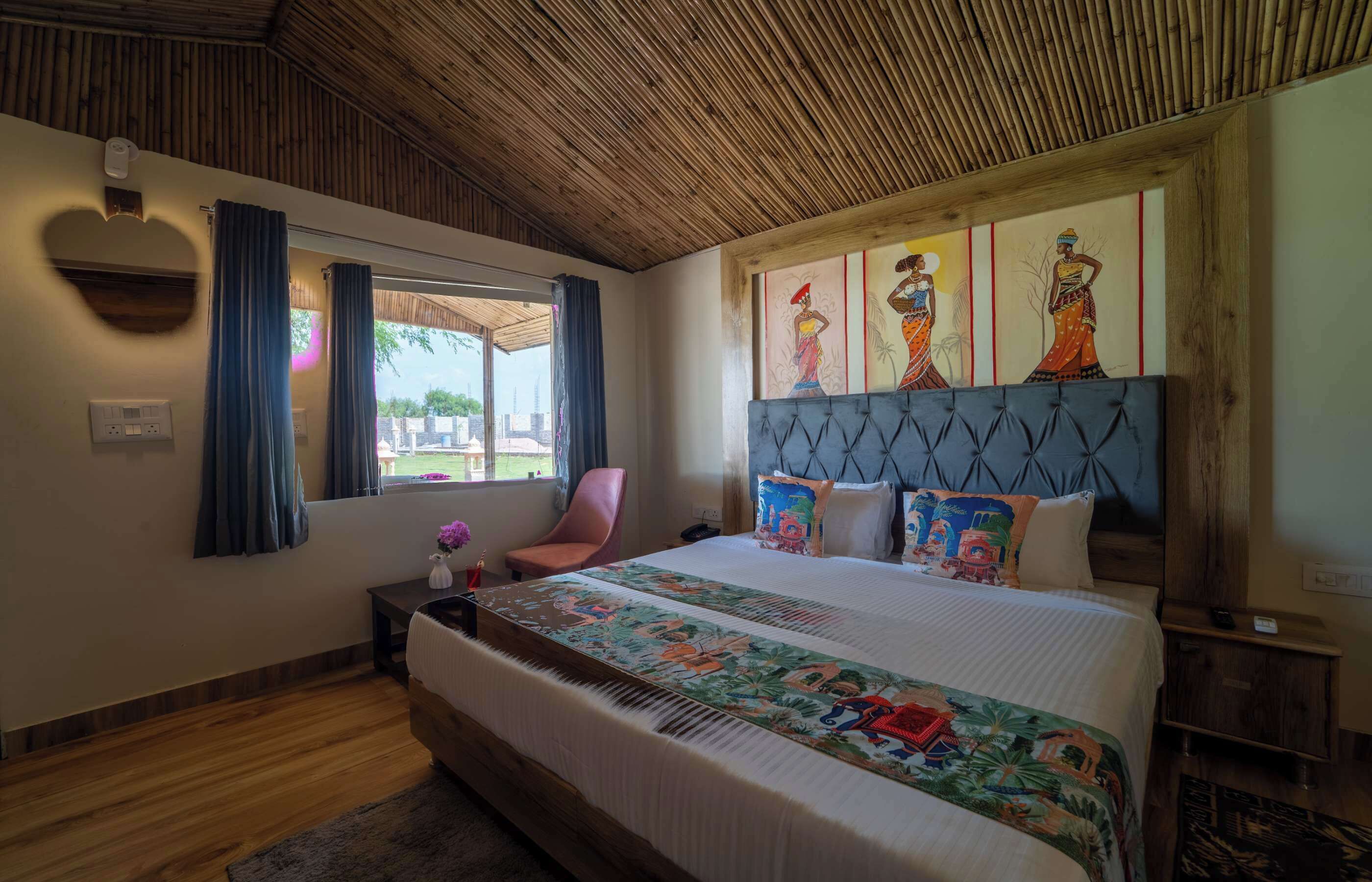 A bedroom with a large bed, a wooden ceiling, a window with curtains, and a wall-mounted artwork.
