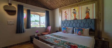 A bedroom with a large bed, a wooden ceiling, a window with curtains, and a wall-mounted artwork.
