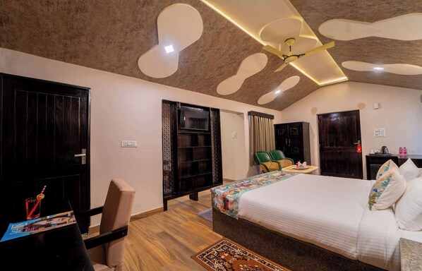 Una camera d'albergo moderna con un letto grande, una scrivania con una sedia, una televisione e una ventola a soffitto.