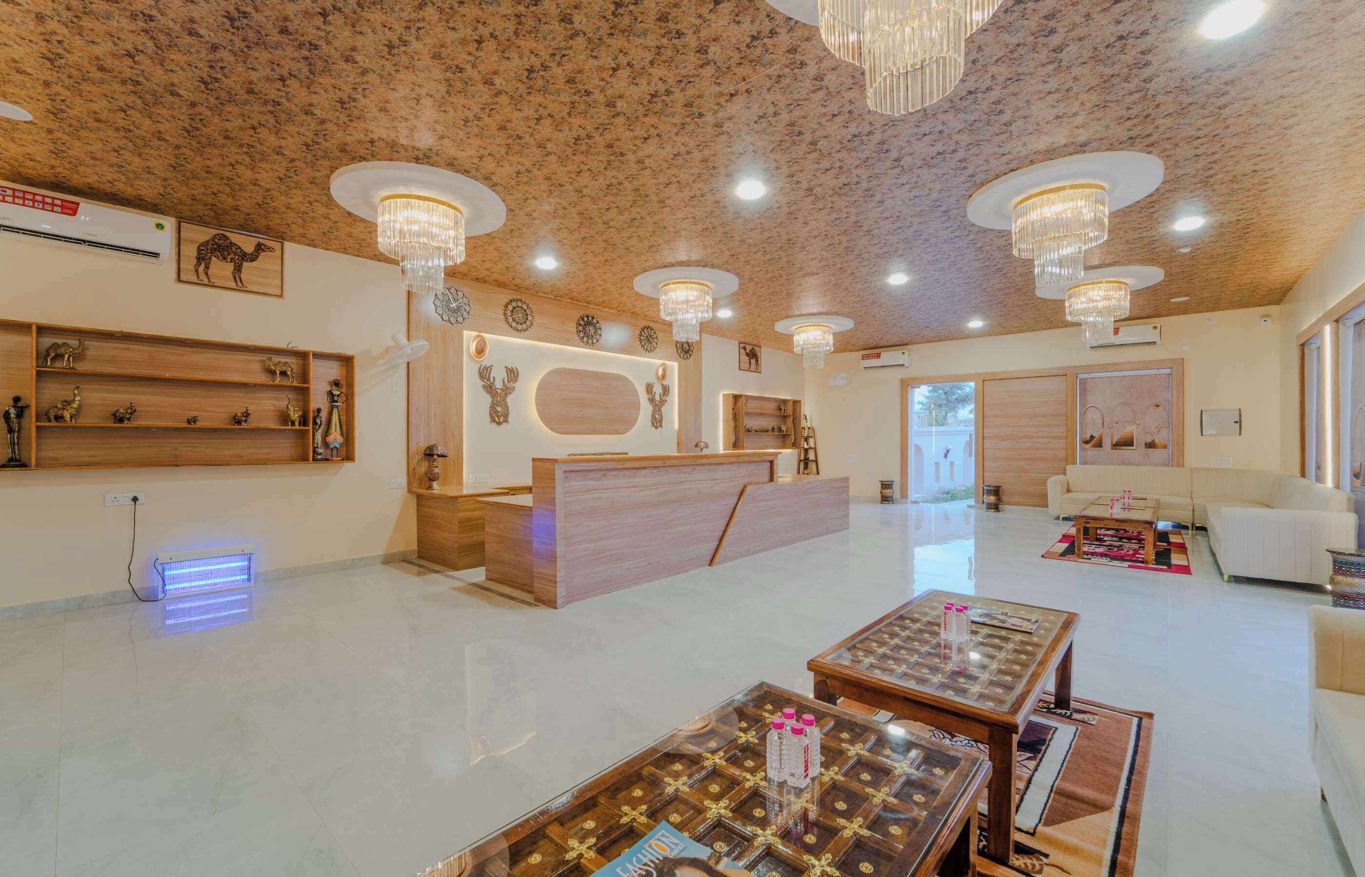 A spacious lobby with a reception desk, multiple seating areas, and decorative elements like wall art and chandeliers.