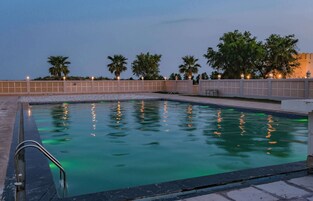 Una piscina con solárium de baldosas y escalera metálica.