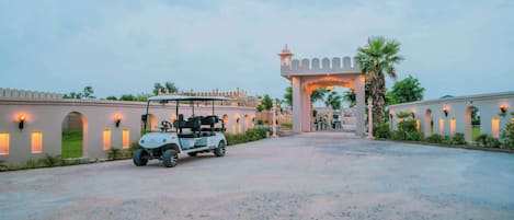 A golf cart parked in front of a traditional building with arched windows and a decorative archway.