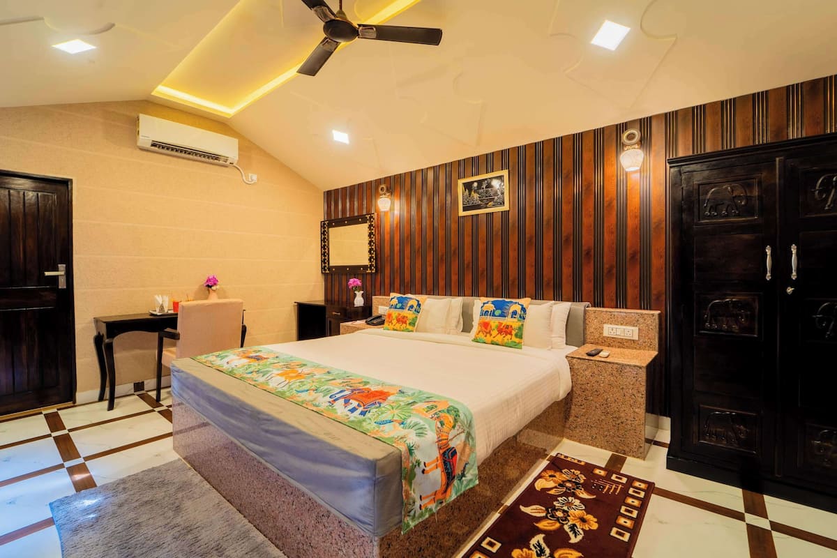 A hotel room with a bed, a desk, a chair, a wardrobe, and a ceiling fan.