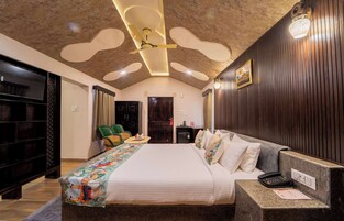 Quarto de hotel moderno com uma cama grande, uma escrivaninha com telefone e um ventilador de teto.
