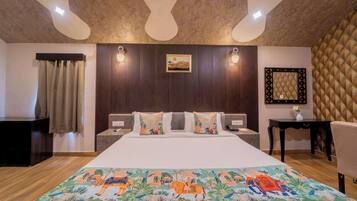 A hotel room with a large bed, wooden headboard, two bedside tables, a nightstand, a decorative rug, and a wall-mounted picture.