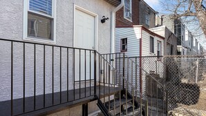 A residential building with a metal railing and a set of stairs leading to a door. - Ututu Stay West (Philadelphia)